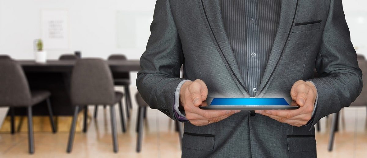 aplikacja mobilna. obrazek przedstawia mężczyznę ubranego w garnitur trzymającego tablet.